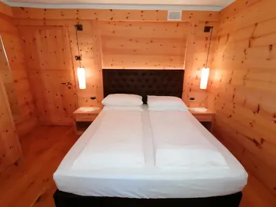 a large bed in a wooden room with two tables at Casa Mariella - Apartment with garden in Tesero