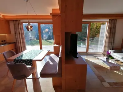 a living room with a dining room table and a tv at Casa Mariella - Apartment with garden in Tesero