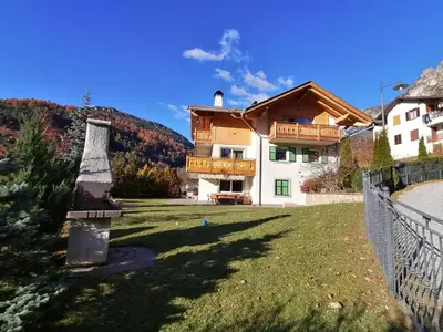 a large house with a fence and a yard at Casa Mariella - Apartment with garden in Tesero