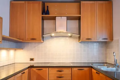 a kitchen with wooden cabinets and a sink at Strategic apartment - near Bolzano in Prato allʼIsarco