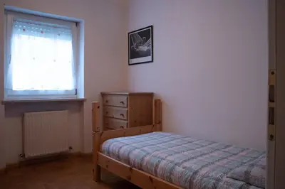 a bedroom with a bed and a dresser and a window at Strategic apartment - near Bolzano in Prato allʼIsarco