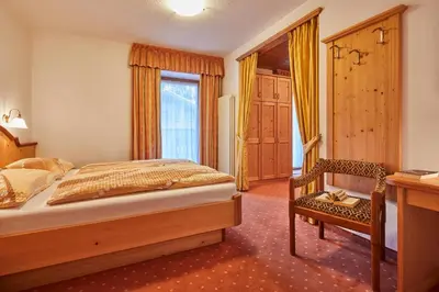 a bedroom with a bed and a desk and a chair at Garni Reutlingen in Colfosco