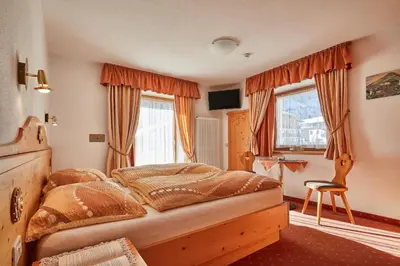 a bedroom with a bed and a desk and windows at Garni Reutlingen in Colfosco