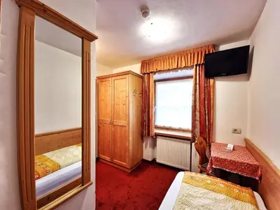 a bedroom with a mirror and a bed and a window at Garni Reutlingen in Colfosco