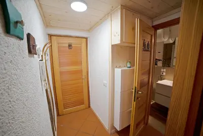 a small bathroom with a refrigerator and a door at Le Nasse in San Martino di Castrozza