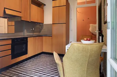 a kitchen with wooden cabinets and a table with a bowl of apples at Appartement Laurin 2 guestcard incl in Merano