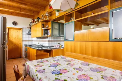 a kitchen with a table with a flowered table cloth at Casa vacanze in Val di Non in Romeno