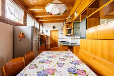 a kitchen with a table and a refrigerator at Casa vacanze in Val di Non in Romeno