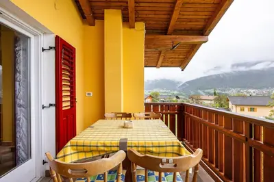 a wooden balcony with a table and chairs on it at Casa vacanze in Val di Non in Romeno