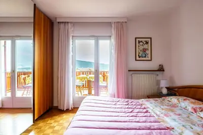 a bedroom with a large bed and a balcony at Casa vacanze in Val di Non in Romeno