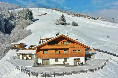 a house on a snow covered mountain with a fence at Residenz Erschbaum in Valdaora