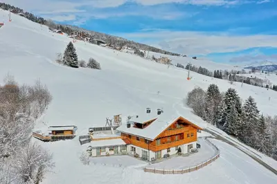 a large wooden house in the snow on a snow covered slope at Residenz Erschbaum in Valdaora
