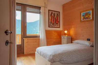 a bedroom with a bed and a large window at Casa Fiore CIPAT 22038 in Canale San Bovo
