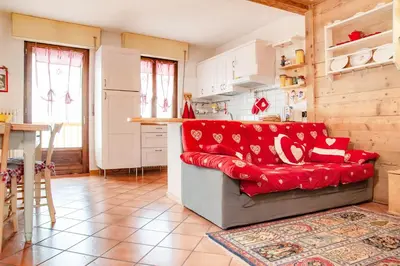 a living room with a red couch in a kitchen at Casa Fiore CIPAT 22038 in Canale San Bovo