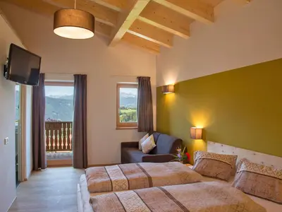 a bedroom with two beds and a couch and a television at Naturhotel Edelweiss in Terento