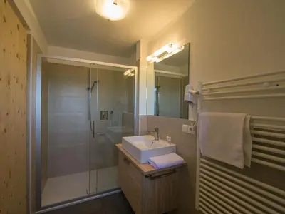 a bathroom with a sink and a shower with a mirror at Naturhotel Edelweiss in Terento