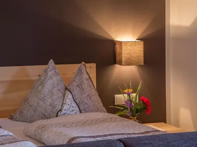 a bedroom with a bed with a vase of flowers at Naturhotel Edelweiss in Terento