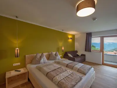 a bedroom with a large bed with a green wall at Naturhotel Edelweiss in Terento