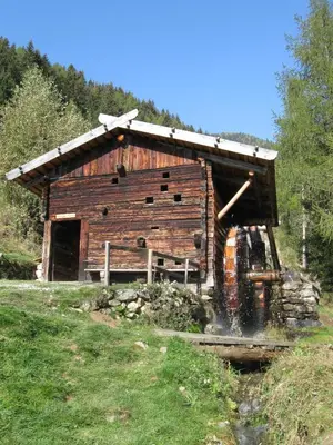 a wooden barn with a roof on a field at Naturhotel Edelweiss in Terento