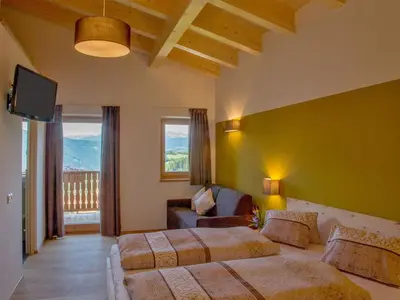 a bedroom with two beds and a couch and a television at Naturhotel Edelweiss in Terento