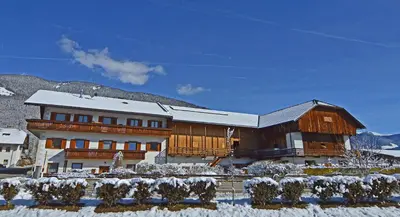 a large wooden building with snow on the ground at Niedermairhof in Falzes