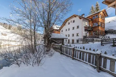 a house in the snow next to a fence at Lüch da Murin in Badia