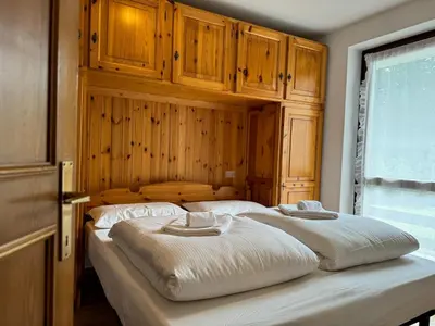 a bedroom with a large bed with wooden cabinets at Family Hut in Carano