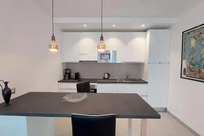 a kitchen with white cabinets and a table with chairs at Casa Grazia - Merano in Merano