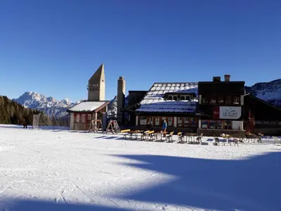 a building with tables and chairs in the snow at Casa Lares in Falcade