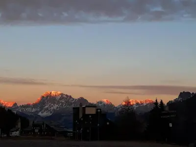 a view of a mountain range with the sun setting at Casa Lares in Falcade