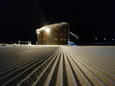 a building with lights in the snow at night at Casa Lares in Falcade
