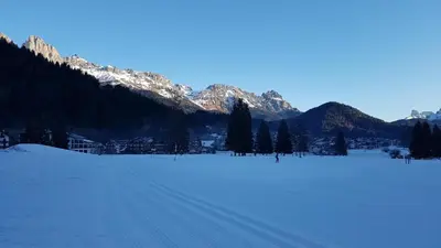 a snow covered field with mountains in the background at Casa Lares in Falcade