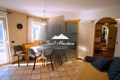 a living room with a dining room table and chairs at Sun & Mountains Cavalese in Cavalese
