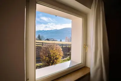 a window with a view of a field outside at Sun & Mountains Cavalese in Cavalese