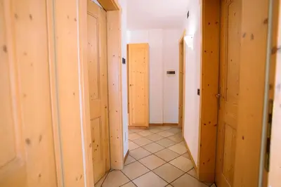 a hallway with wooden doors and a tile floor at Sun & Mountains Cavalese in Cavalese