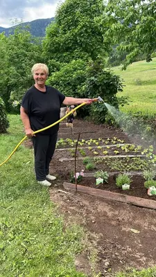 a woman watering a garden with a hose at Respira il Bosco in Anterivo