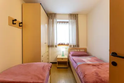 two beds in a small room with a window at CASA BRUNELLA in Cavalese