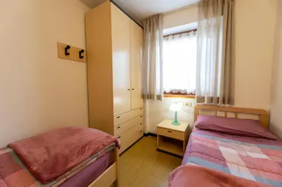 a small bedroom with two beds and a window at CASA BRUNELLA in Cavalese