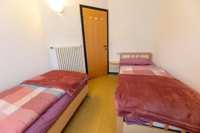 two beds in a room with a hallway with a door at CASA BRUNELLA in Cavalese