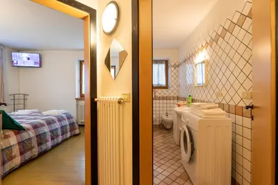 a bathroom with a sink and a toilet and a bed at CASA BRUNELLA in Cavalese