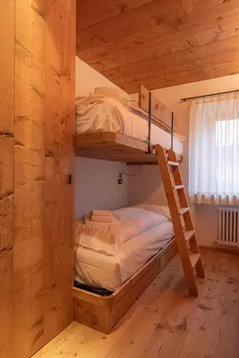 a bunk bed in a wooden room with a ladder at Casa Alvera Dream in Cortina dʼAmpezzo