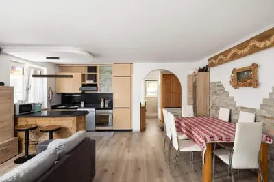 a kitchen and living room with a table and a couch at Casa Lucia Moena in Moena