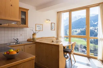 a kitchen with a table and a large window at Apartments Etruska Gabriela in Santa Cristina in Val Gardena