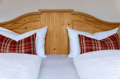 a bedroom with two beds with white sheets and red pillows at Apartments Etruska Gabriela in Santa Cristina in Val Gardena