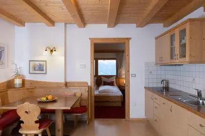 a kitchen with a table and a room with a bed at Apartments Etruska Gabriela in Santa Cristina in Val Gardena