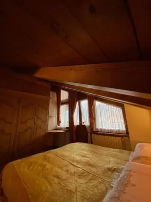 an attic room with a bed and two windows at Chalet Panorama Dolomiti vicino piste, centro e Cortina in San Vito di Cadore