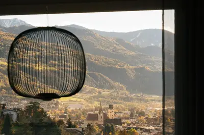 a large chandelier hanging from a window with mountains at Cityview Brixen in Bressanone