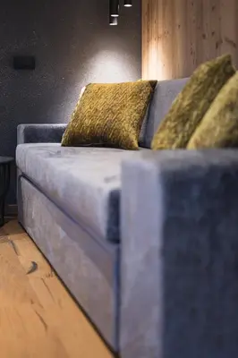 a blue couch with two yellow pillows on it at DOLOMITI EXCLUSIVE YOUR MOUNTAIN SUITE in Pozza di Fassa