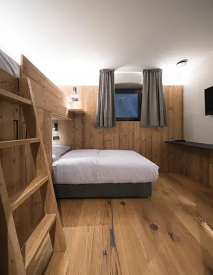 a bedroom with a large bed and wooden floors at DOLOMITI EXCLUSIVE YOUR MOUNTAIN SUITE in Pozza di Fassa