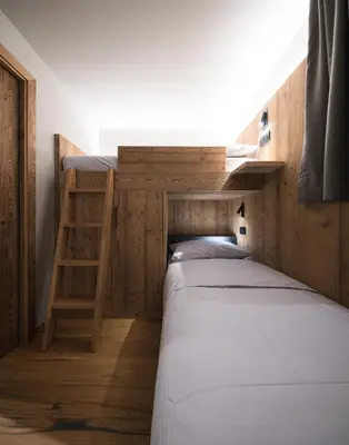 two beds in a bunk room with a ladder at DOLOMITI EXCLUSIVE YOUR MOUNTAIN SUITE in Pozza di Fassa